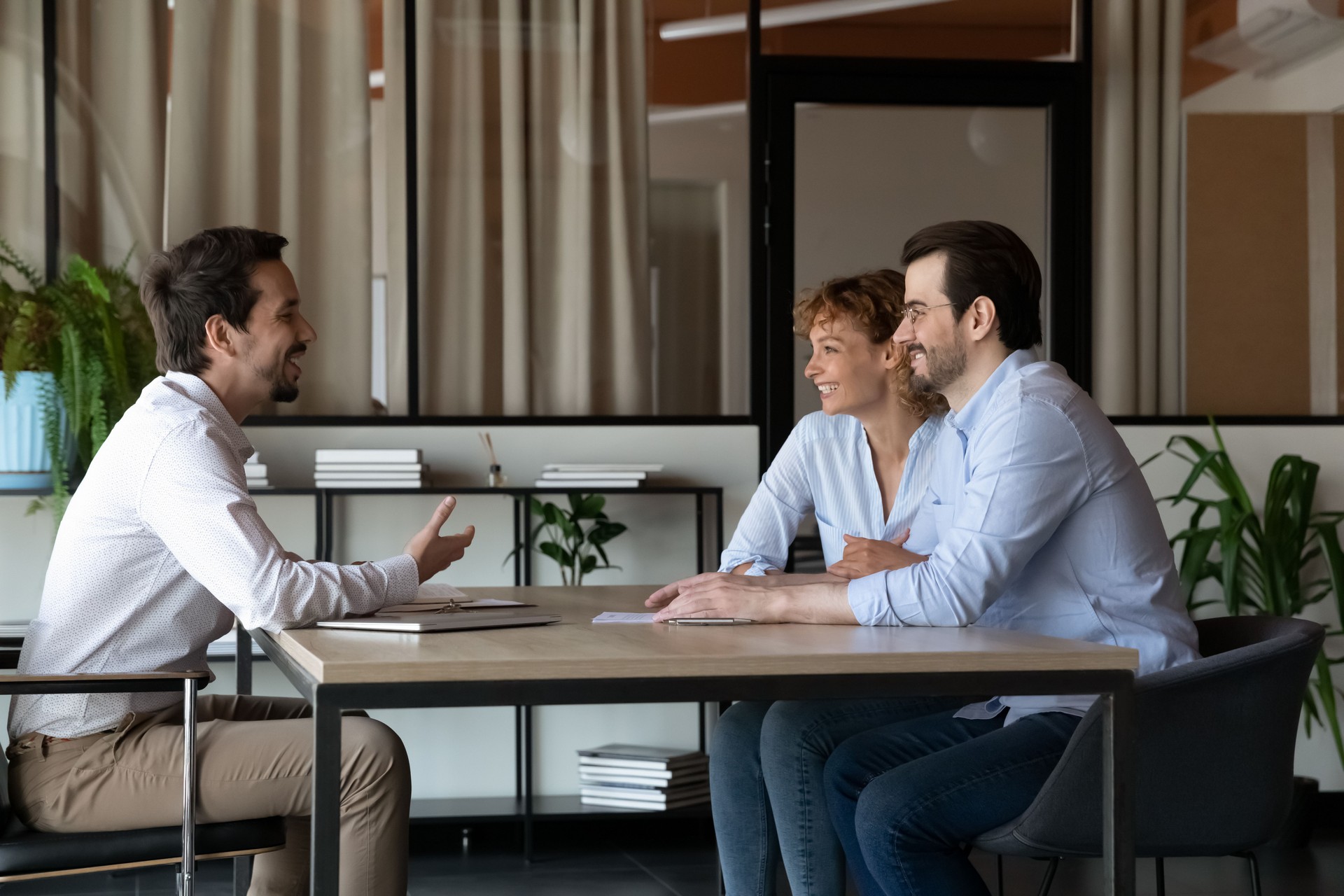Coppia di clienti felici della famiglia che si incontrano con l'agente immobiliare